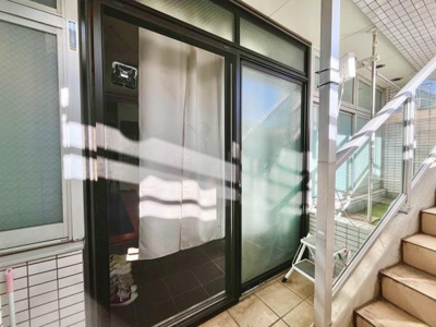 大きなガラス引き戸が印象的な玄関です。明るい光が差し込む開放的な印象を与えます。隣接の階段や屋根付きの通路が便利です。室内へのアクセスがスムーズで外からの目線も配慮された設計になっています。