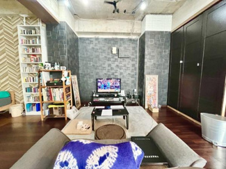 コンクリート天井とブラックの壁面が特徴的なリビングです。開放感のある空間が広がっています。収納ラックや本棚が設置されており整理整頓がしやすいです。