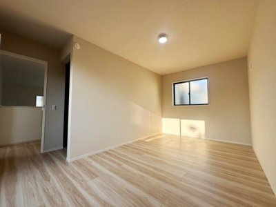 ナチュラルな色合いのフローリングが特徴の洋室です。シンプルな内装が落ち着いた雰囲気を演出しています。窓から光が差し込み空間が明るく感じられます。照明設備も備わっており使いやすい設計です。