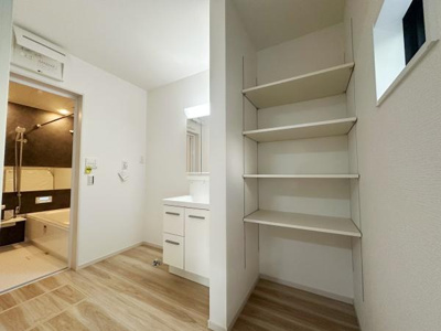 壁面に設置された棚で空間を有効活用できる収納です。洗面台のすぐそばにあり日常の動線にも便利です。ナチュラルなフローリングと組み合わせたデザインが印象的です。浴室との導線もスムーズです。