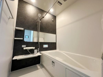 シンプルなデザインのバスルームでお手入れがしやすい仕様です。広々とした浴槽があり使い勝手のよい空間です。大きな鏡とシャワースペースが設けられています。清潔感のある色合いが印象的です。