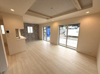 広々としたリビング空間が明るさを引き立てます。大きな窓からたっぷりと自然光が差し込みます。白を基調とした床材が室内全体を開放的に演出します。天井のアクセント梁がデザイン性を高めています。