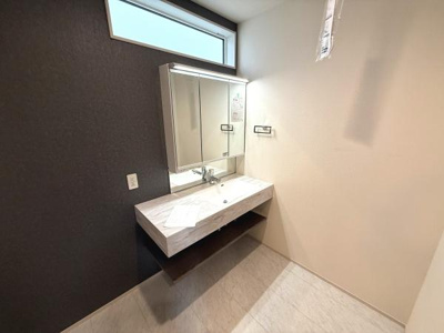 洗面台にはスタイリッシュなデザインが採用されています。大きな鏡が設置されており身支度にも便利です。上部の窓からは自然光が差し込み空間が明るく感じられます。