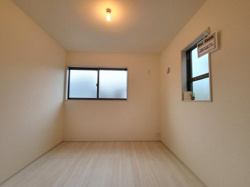 明るい照明と2つの窓から自然光が入る洋室です。シンプルな内装なので家具のレイアウトがしやすいです。壁面にコンセントもあり使い勝手の良い空間です。ナチュラルな木目調の床が印象的です。