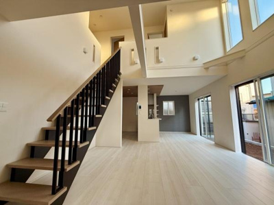 吹き抜けのデザインが開放感を演出しています。大きな窓から心地よい光が差し込みます。明るいフローリングが空間を広々と見せます。階段のデザインもアクセントになっています。