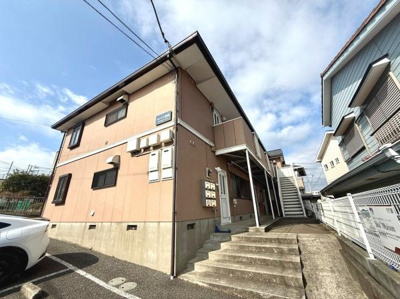 二階建ての落ち着いた外観が特徴的な物件です。敷地内に専用の駐車スペースが確保されています。建物周辺はスロープや階段も整備されアクセスしやすい環境です。日当たりも期待できる配置で明るさが感じられます。