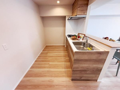 ナチュラルな木目調のデザインが空間に調和しています。シンク横には広めのワークスペースがあり天井にはダウンライトを備えています。キッチン周りがすっきりとした印象で清潔感があります。