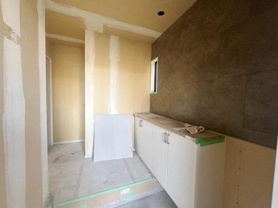 玄関にはシンプルで落ち着いた色合いのデザインが採用されています。収納も設けられており使いやすさが感じられます。小窓からの採光により明るさが確保されています。壁面の質感が空間にアクセントを加えています。