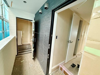 玄関からすぐにアクセスできる便利な動線が特徴です。黒いアクセント壁が空間を引き締めています。バルコニーからは明るい光が差し込み開放感も感じられます。シンプルな内装がすっきりとした印象を与えています。