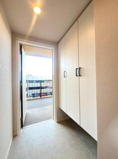 玄関には大型の収納スペースが備わっております。明るい照明が空間をしっかり照らします。玄関からバルコニーへの動線が確保されており換気もスムーズです。白を基調とした内装で清潔感があります。