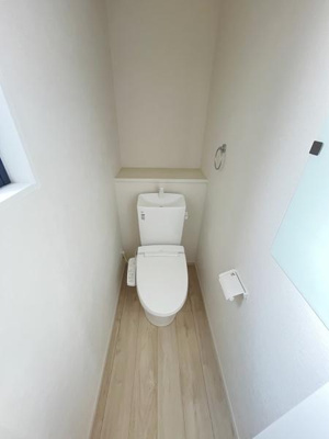 明るい色調の床と壁が調和したトイレです。コンパクトな空間設計で使いやすさを重視しています。窓からの採光があり清潔感が感じられるつくりです。収納スペースも確保されています。