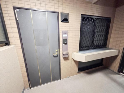 玄関ドアはシンプルなデザインで落ち着いた雰囲気です。窓には格子が設置されており防犯面にも配慮されています。インターホン付きで来客時の対応も安心です。玄関前のスペースが広めに確保されています。