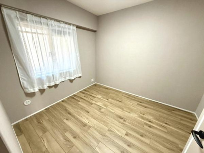 明るい光が差し込む洋室です。落ち着いた色合いの壁とフローリングが調和しています。シンプルなデザインでコーディネートがしやすい空間です。窓付きで換気もスムーズです。広々とした床面が確保されています。