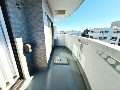 バルコニーはゆとりあるスペースが確保されています。タイル張りの壁面がアクセントとなっています。周囲の景色を楽しめる開放的な眺望です。物干し金具が設置されており機能性も備えています。