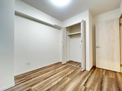 明るい色合いの床材が室内をすっきりと見せています。クローゼット付きで収納スペースも確保されています。シンプルな壁面がインテリアを選びやすくしています。ドアや建具も統一感のあるデザインです。