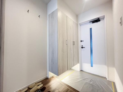 玄関は明るい雰囲気で清潔感のある空間です。収納スペースも豊富に確保されています。床の木目調がやさしい印象を与えます。シンプルなデザインで使い勝手が良いです。スリッパも並べやすいスペースがあります。