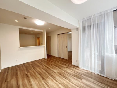 明るい色合いのフローリングが室内を開放的に演出します。大きな窓から自然光がたっぷり入ります。キッチンとのつながりも感じられるリビングです。シンプルな内装で家具の配置がしやすい空間です。