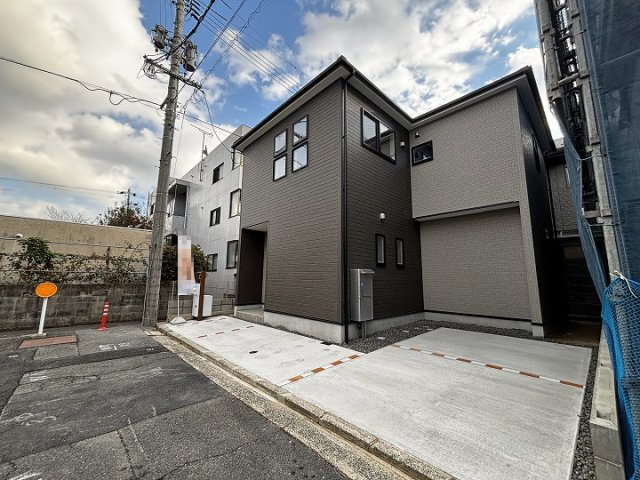 ダークトーンを基調とした落ち着きのある外観。建物前面にはコンクリート舗装された駐車スペースを確保しています。